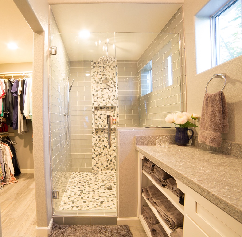 Sophisticated Master Bathroom remodel in gray and white color palette. Double shower features gray polished glass subway tile with a decorative band and shower floor in a pebble blend tile. [TWD Project Location: Goodyear, AZ]