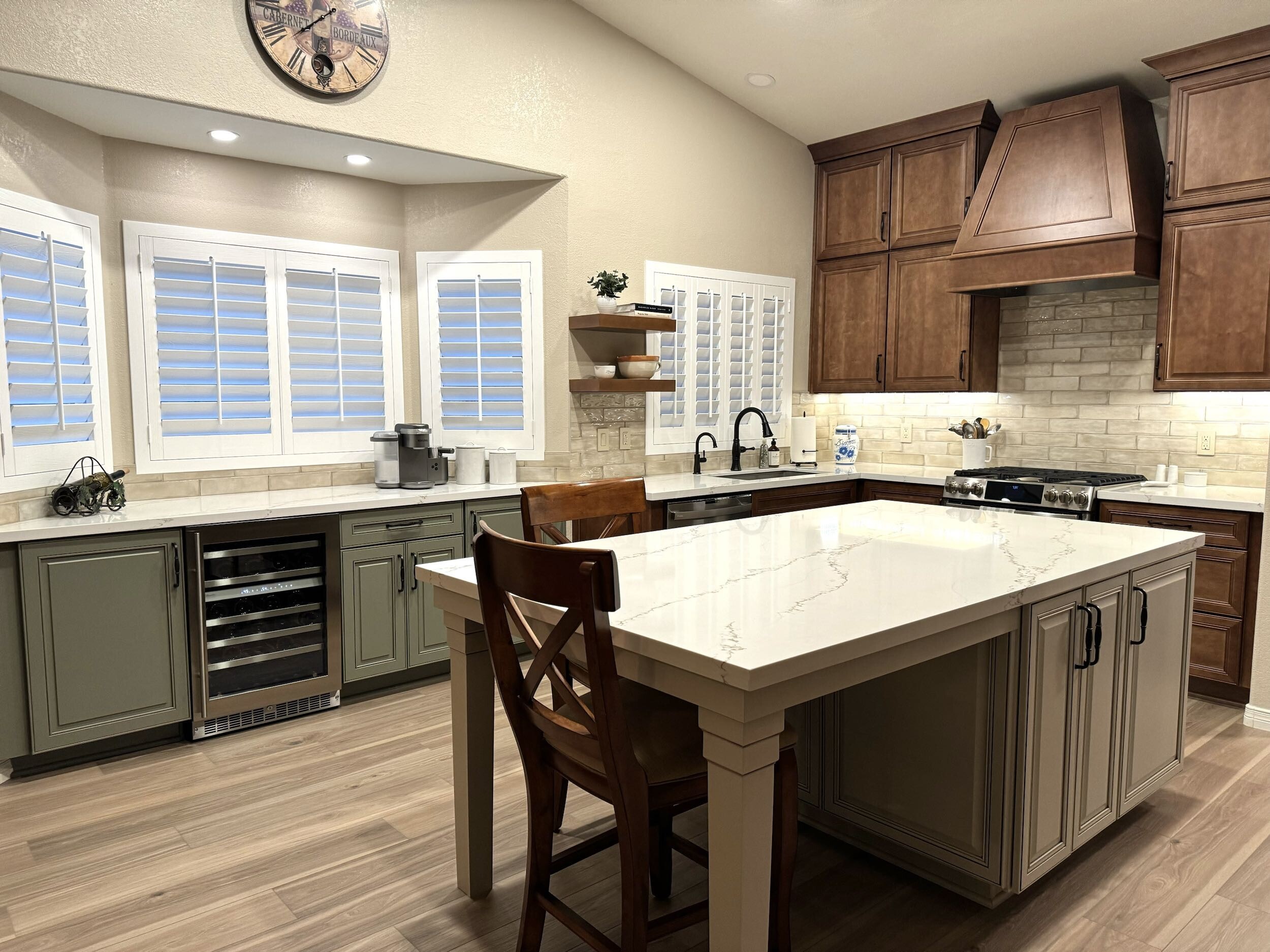 Tri-color cabinetry in this farmhouse style kitchen remodel. Wellborn Cabinet Select series cabinetry with a Concord door style used in the kitchen. The island was done in Gray Mist, while the perimeter cabinets are in Carmel. The built-in bar area however is Olive color with a Monteray door style.  [TWD Project Location: Phoenix, AZ]