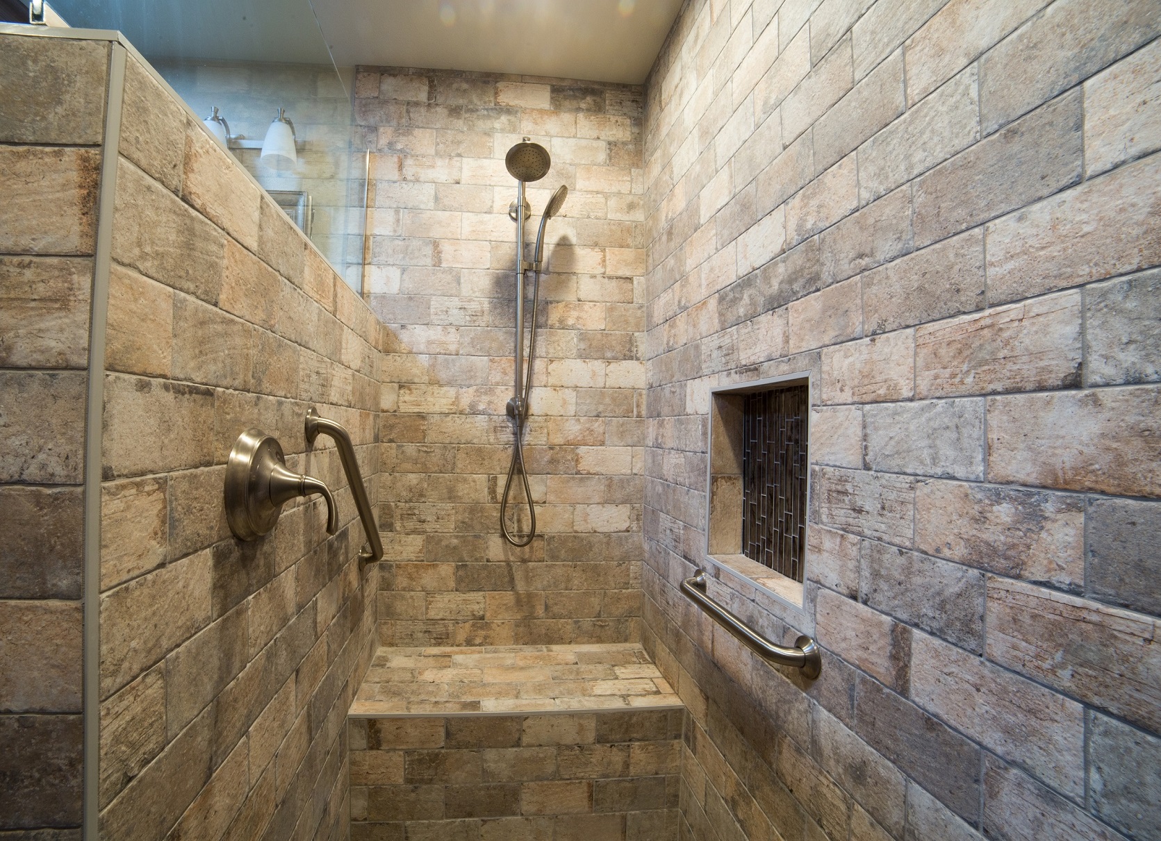 Chicago Brick Southside porcelain tile, full width bench seating, shampoo niche within reach, and handheld shower complete this stunning Master Bathroom design. [TWD Project Location: Sun City West, AZ]