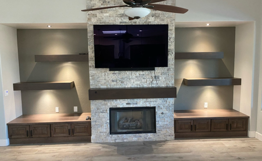 Stone feature wall, floating shelves, and Wellborn Cabinetry in Java color complete the look of this media wall. [TWD Project Location: Surprise, AZ]