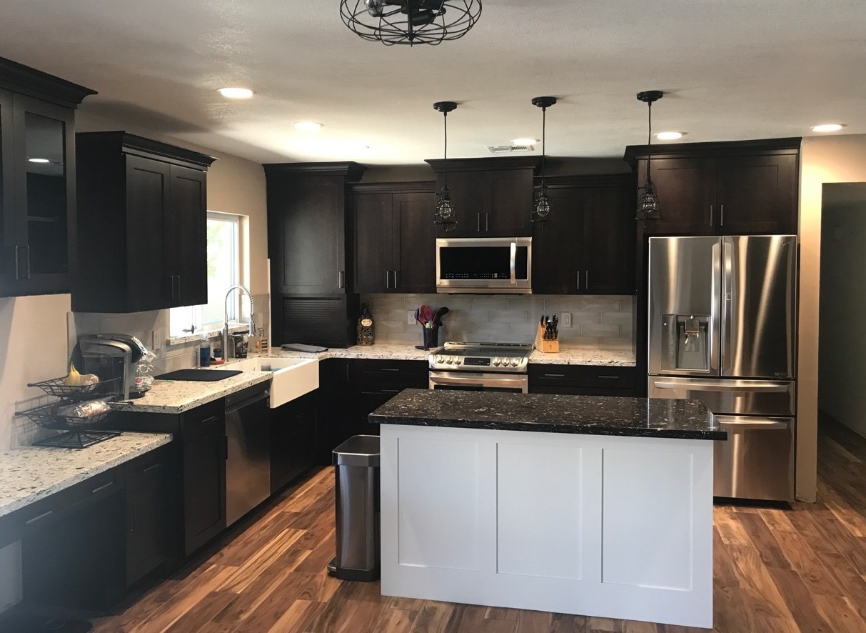 Wellborn Cabinetry in an Espresso finish paired with Quartz Arctic countertops at the perimeter of the kitchen with Glacier White cabinets topped with Volcano Quartz countertops at the island create a beautiful fresh and modern kitchen design. Subway tile and farmhouse sink in white to match. [TWD Project Location: Glendale, AZ]