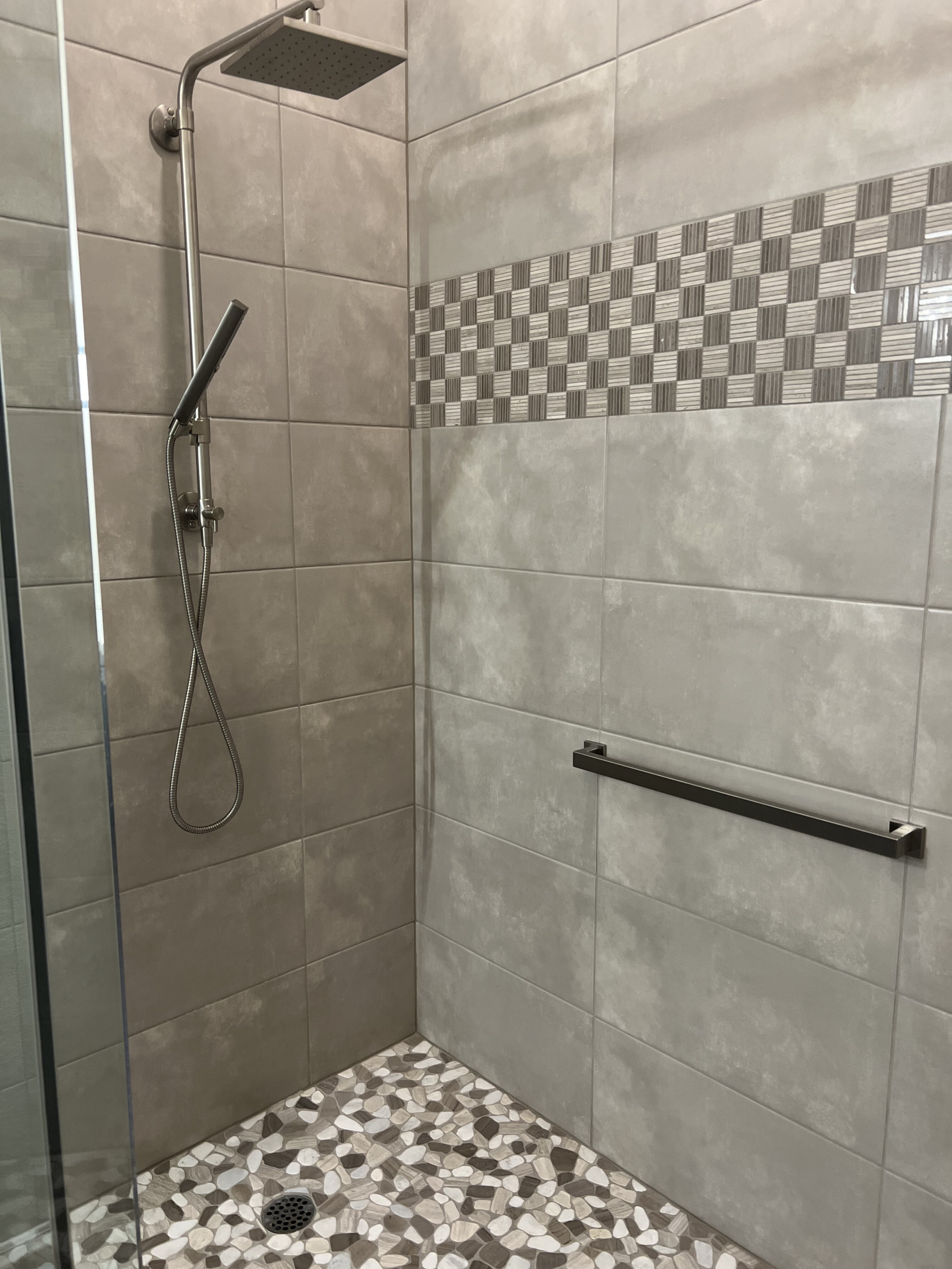 Bathroom remodel showcasing 12" x 24" wall tile with deco tile band and pebble tile floor. Brushed nickel fixtures to perfectly complete this new shower. [TWD Project Location: Scottsdale, AZ]