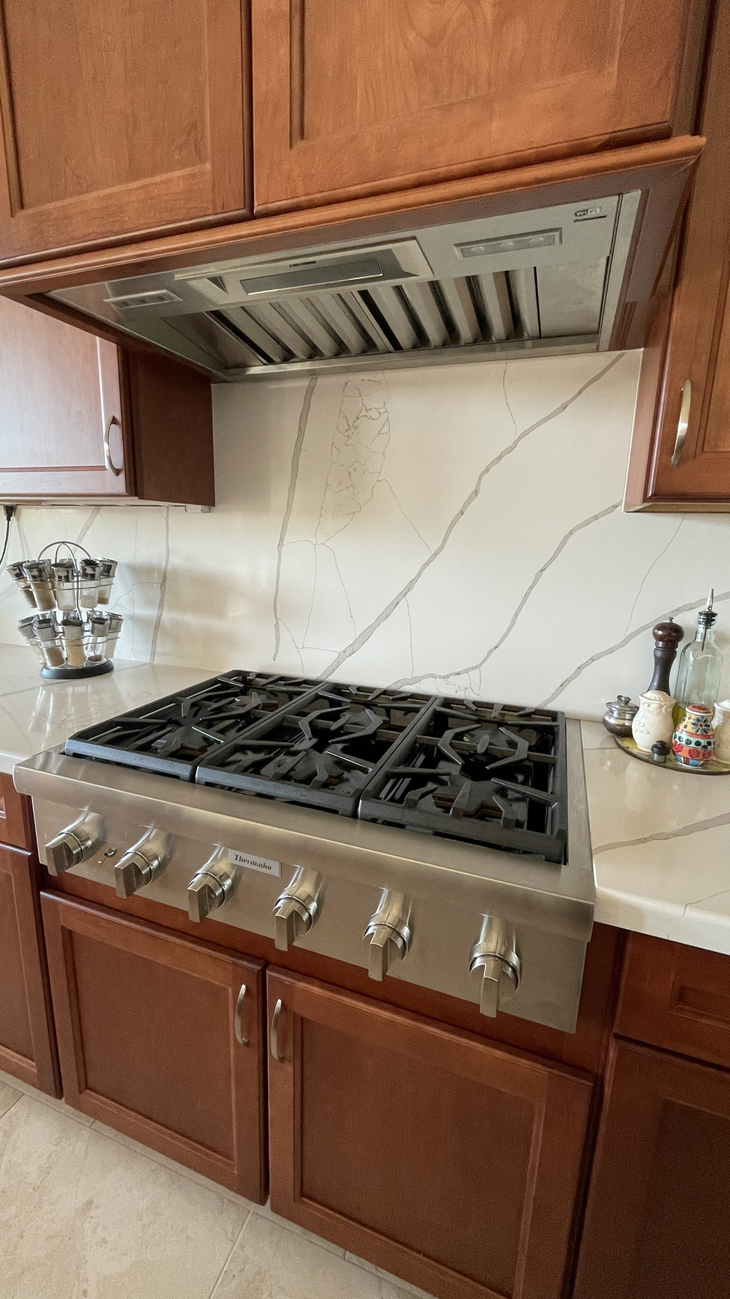 Gorgeous cherry cabinet kitchen showing Wellborn Cabinets in Millbrook door style. The polished quartz Calacatta Laza Gold countertops have just the right amount of veining to add contrast and character against the cherry cabinetry. [TWD Project Location: Scottsdale, AZ]