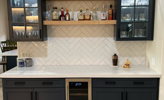 This home bar/beverage center utilizes the same Navy cabinetry by Waypoint that we used to remodel the kitchen, open shelving, 3" x 12" Spanish glazed tile in a herringbone pattern, and gorgeous matching quartz tops. [TWD Project Location: Glendale, AZ]