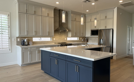 This once builder-grade kitchen now is classy and sophisticated. Showcasing two-toned cabinetry from Waypoint Living Spaces in Harbor for the perimeter cabinets that reach to the ceiling, and Navy for the oversized l-shaped island. [TWD Project Location: Cave Creek, AZ]