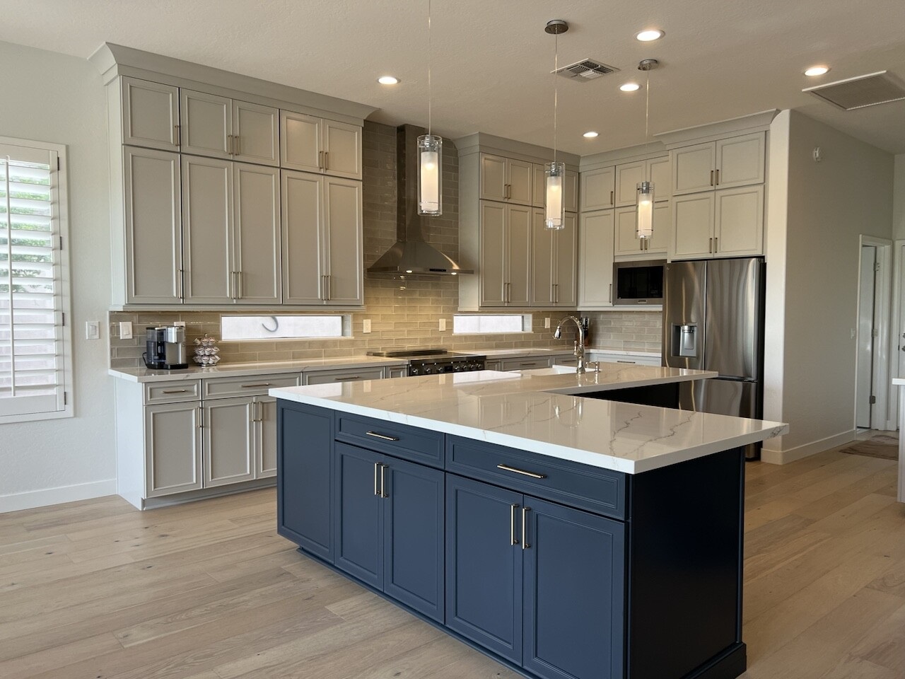 This once builder-grade kitchen now is classy and sophisticated. Showcasing two-toned cabinetry from Waypoint Living Spaces in Harbor for the perimeter cabinets that reach to the ceiling, and Navy for the oversized l-shaped island. [TWD Project Location: Cave Creek, AZ]