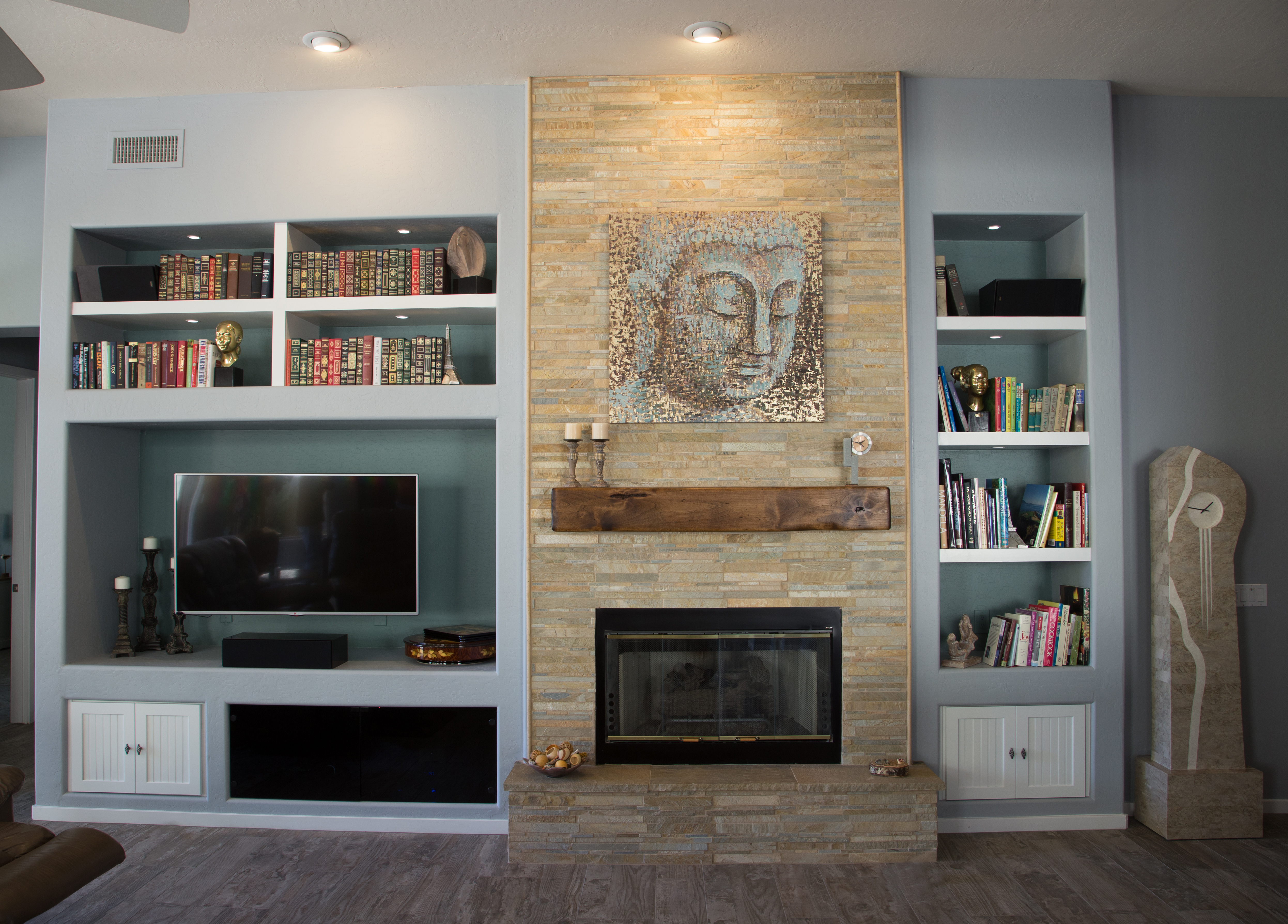 TWD built a custom drywall and cabinetry media center in the spacious living area that can be seen from the kitchen. The design was created around the customers artwork as the focal point of the space. Smoked glass A/V doors, a custom wood mantle, electrical relocations, LED lighting upgrades and beautiful stacked stone on the fireplace surround complete the welcoming vibe that this customer was going for. [TWD Project Location: Scottsdale, AZ]