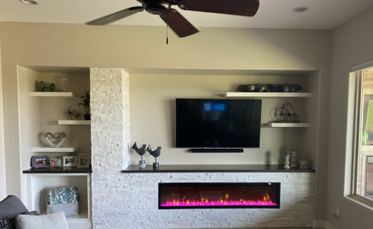 A custom media wall such as this is inclusive of TWD framing out the new design, electrical upgrades as needed, Wellborn Cabinetry floating shelves, Silestone quartz slab used on top of the cabinetry and the fireplace ledge, Artic White stone used around the fireplace and up the column, and the necessary additional support for the wall mounted television (fireplace supplied and installed by Others). [TWD Project Location: Peoria, AZ]