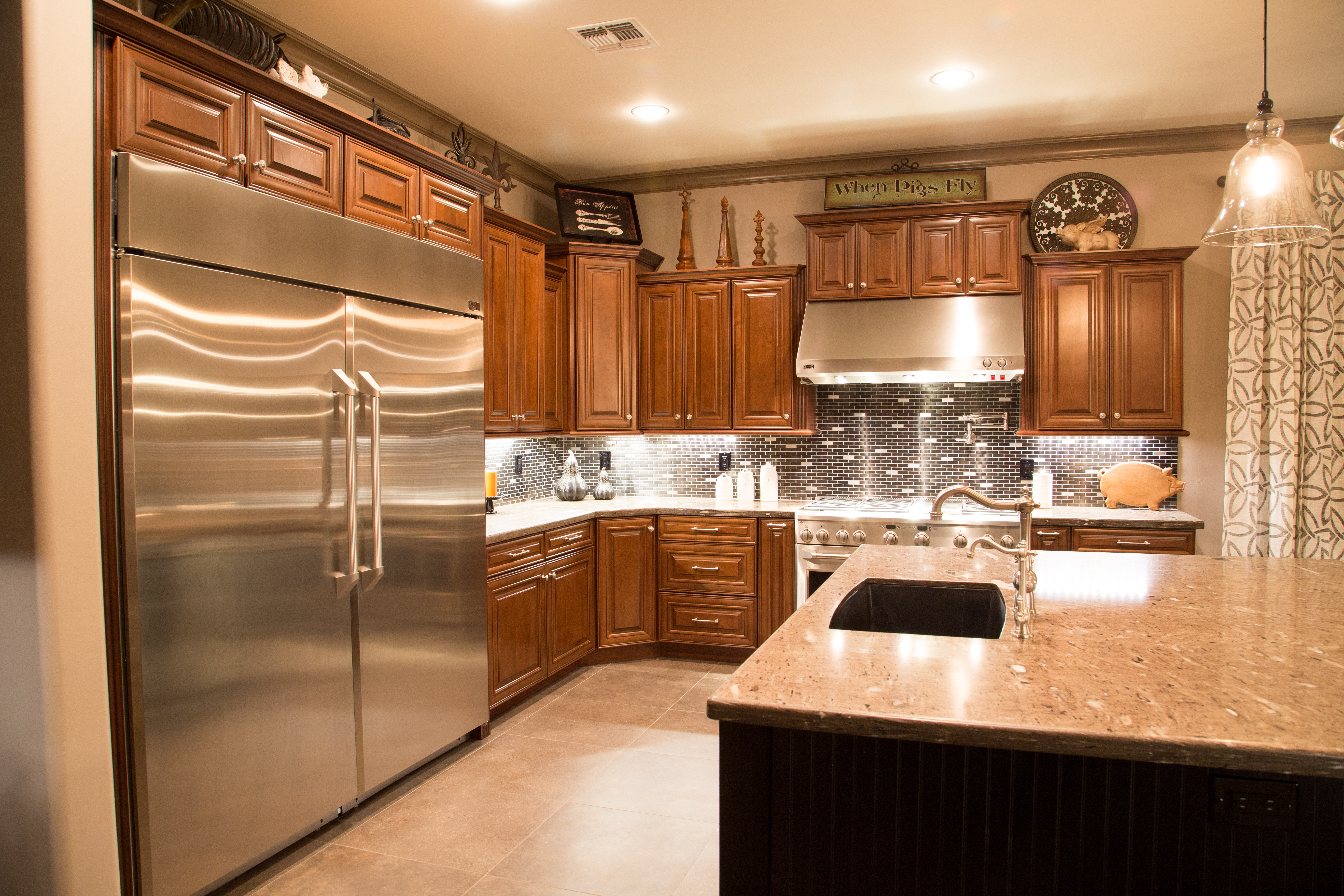 GE Monogram 36" Refrigerator and 36" Freezer, 48" Pro Wall Hood with a 48" range with griddle, an over-sized island with ample prep space topped with new Bordeaux granite countertops and a black metal brick backsplash are just a few of this remodeled Kitchen's features that will attract your attention. [TWD Project Location: Surprise, AZ]