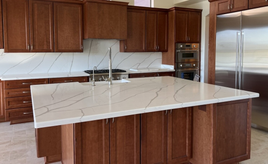 Gorgeous cherry cabinet kitchen showing Wellborn Cabinets in Millbrook door style. The polished quartz Calacatta Laza Gold countertops have just the right amount of veining to add contrast and character against the cherry cabinetry. [TWD Project Location: Scottsdale, AZ]