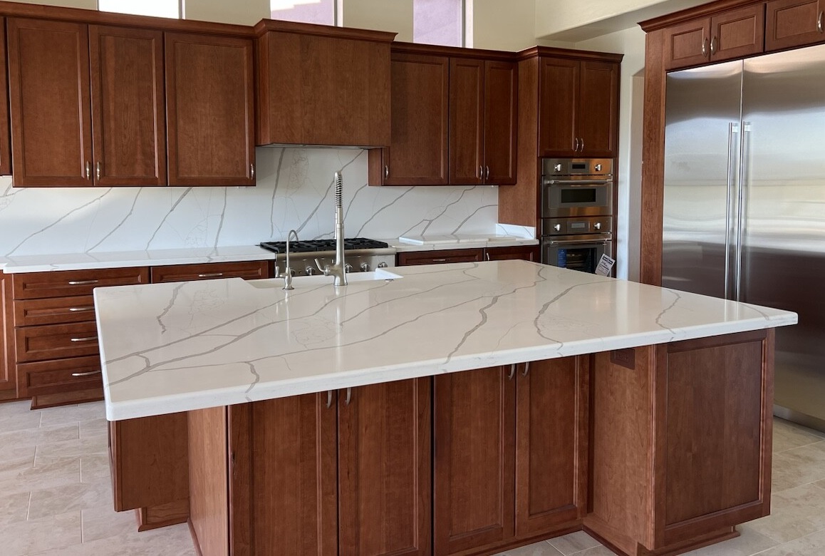 Gorgeous cherry cabinet kitchen showing Wellborn Cabinets in Millbrook door style. The polished quartz Calacatta Laza Gold countertops have just the right amount of veining to add contrast and character against the cherry cabinetry. [TWD Project Location: Scottsdale, AZ]